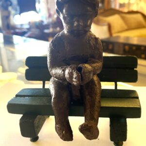 Vintage bronze sculpture of a child on a green timber bench